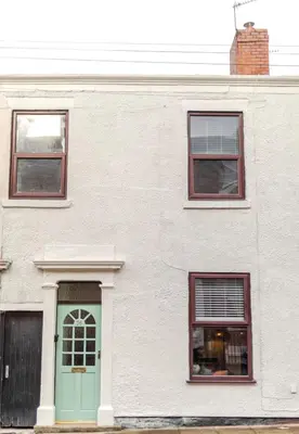 a white building with a green door and two windows at Cosy city centre home - Wi-Fi - Free Parking in Preston