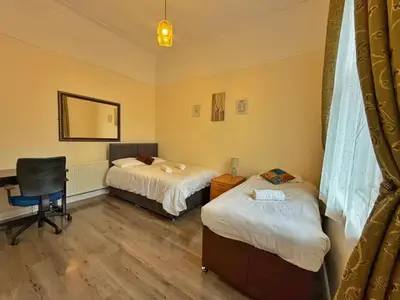 a room with two beds and a desk and a chair at Near City-Birkenhead rooms in Birkenhead