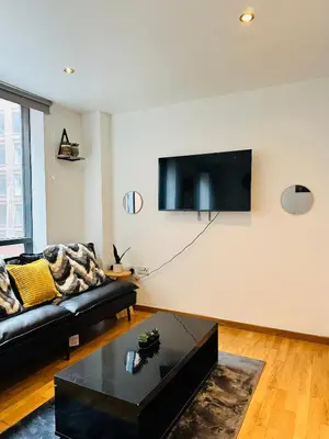 a living room with a couch and a tv on a wall at Longterm Stay City Centre Apartment 2 Bedrooms in Liverpool