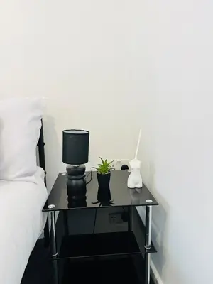 a nightstand with a lamp and a plant on it next to a bed at Longterm Stay City Centre Apartment 2 Bedrooms in Liverpool