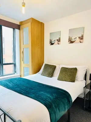 a bedroom with a large bed with a blue blanket on it at Longterm Stay City Centre Apartment 2 Bedrooms in Liverpool