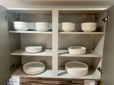 a cupboard filled with white plates and bowls at New Modern 3 Bed En-suites City Centre Apartment - Sleeps 8- Paid Parking Options in Preston