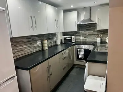 a kitchen with white cabinets and black counter tops at New Modern 3 Bed En-suites City Centre Apartment - Sleeps 8- Paid Parking Options in Preston