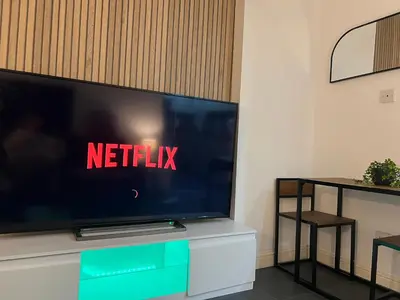 a flat screen tv sitting on top of a white cabinet at New Modern 3 Bed En-suites City Centre Apartment - Sleeps 8- Paid Parking Options in Preston