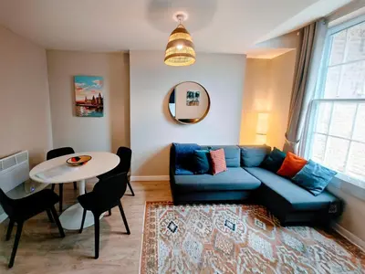 a living room with a blue couch and a table at Victoria's Bright Georgian Apartment in Liverpool