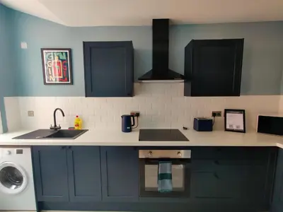 a kitchen with black cabinets and a sink and a washer at Victoria's Bright Georgian Apartment in Liverpool