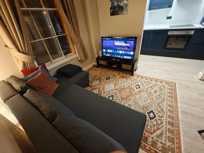 a living room with a couch and a flat screen tv at Victoria's Bright Georgian Apartment in Liverpool