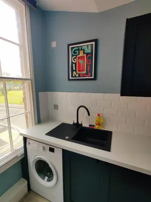 a kitchen with a sink and a washing machine at Victoria's Bright Georgian Apartment in Liverpool
