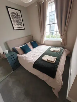 a bedroom with a bed with blue pillows and a window at Victoria's Bright Georgian Apartment in Liverpool