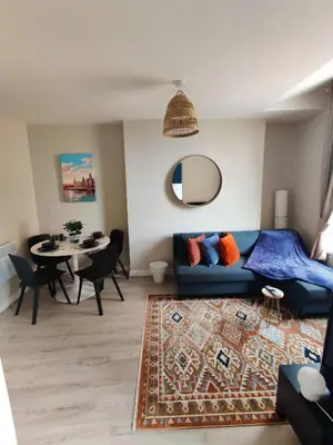 a living room with a blue couch and a table at Victoria's Bright Georgian Apartment in Liverpool