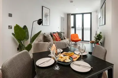 a dining room with a table with plates and wine glasses at River Mersey Views Modern 2-Bed Waterfront Flat Near Albert Dock in Liverpool