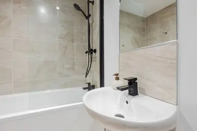 a white bathroom with a sink and a shower at River Mersey Views Modern 2-Bed Waterfront Flat Near Albert Dock in Liverpool
