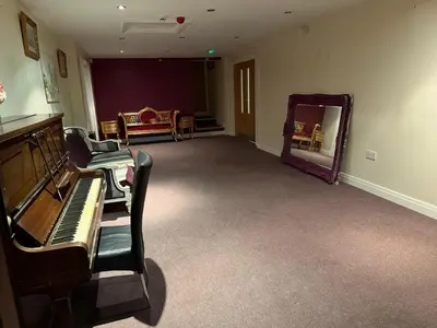 a living room with a piano and a mirror at Art Group Apartments in Fleetwood