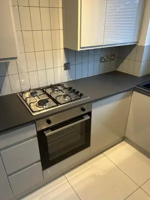 a kitchen with a stove and white cabinets at Cosy Apartment in Wallasey Village Near Liverpool in Wallasey