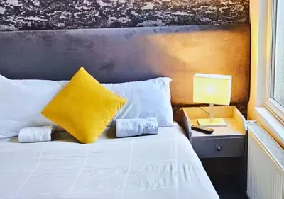 a bedroom with a bed with a yellow pillow and a lamp at Pitchside Place Walk to Anfield sleeps 19 in Liverpool