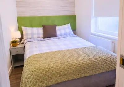 a bedroom with a bed with a green headboard at Pitchside Place Walk to Anfield sleeps 19 in Liverpool