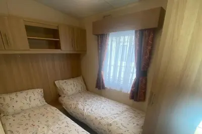 a small room with two beds and a window at 2 Bed Caravan-Sleeps 6-Pet Friendly in Carnforth