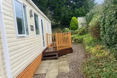 a house with a wooden deck next to a building at 2 Bed Caravan-Sleeps 6-Pet Friendly in Carnforth