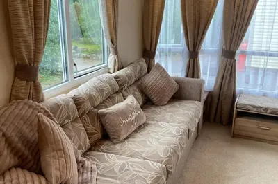 a couch in a living room with windows at 2 Bed Caravan-Sleeps 6-Pet Friendly in Carnforth