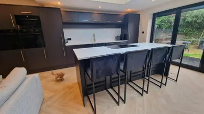 a kitchen with black cabinets and a white counter top at Birkdale Open - modern 3 bedroom family home in Ainsdale