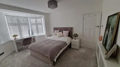 a bedroom with a bed and a desk and windows at Birkdale Open - modern 3 bedroom family home in Ainsdale