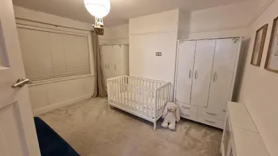 a baby room with a crib and a refrigerator at Birkdale Open - modern 3 bedroom family home in Ainsdale