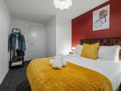 a bedroom with a large bed with a yellow blanket at Spacious City Stay 2BR 2BA Parking Included in Liverpool