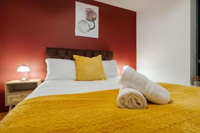 a bedroom with a large bed with a yellow blanket at Spacious City Stay 2BR 2BA Parking Included in Liverpool