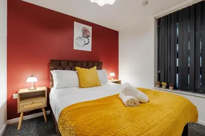 a bedroom with a large bed with a yellow blanket at Spacious City Stay 2BR 2BA Parking Included in Liverpool