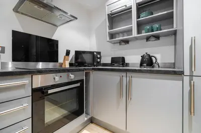 a kitchen with white cabinets and a stove top oven at Spacious City Stay 2BR 2BA Parking Included in Liverpool