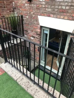 a black fence with green grass in front of a building at 2 Bedroom City Centre Georgian Quarter Apartment in Liverpool