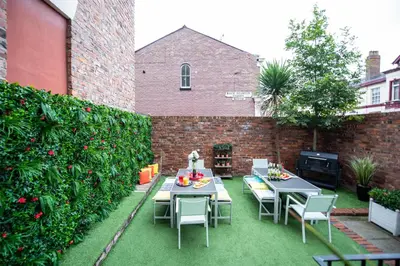 a patio with tables and chairs and a brick wall at 2 Bedroom City Centre Georgian Quarter Apartment in Liverpool
