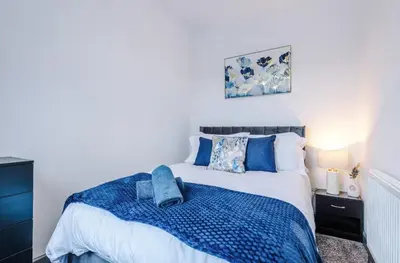 a bedroom with a bed with a blue blanket at Three Bedroom House in Wigan - Perfect for family! in Ince-in-Makerfield