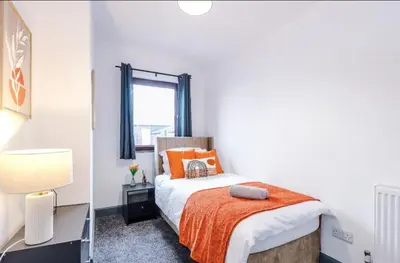 a bedroom with a bed with an orange blanket at Three Bedroom House in Wigan - Perfect for family! in Ince-in-Makerfield