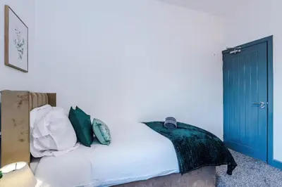 a bedroom with a bed with green and white pillows at Three Bedroom House in Wigan - Perfect for family! in Ince-in-Makerfield