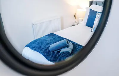 a mirror reflection of a bed with a blue blanket at Three Bedroom House in Wigan - Perfect for family! in Ince-in-Makerfield