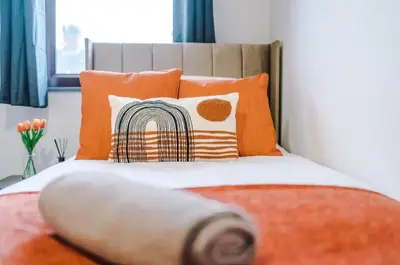 a bedroom with a bed with orange pillows at Three Bedroom House in Wigan - Perfect for family! in Ince-in-Makerfield
