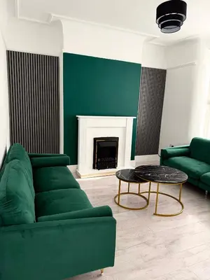 a living room with a green couch and a fireplace at D&D Emerald House Anfield in Liverpool