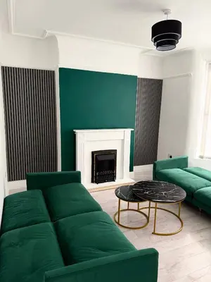 a living room with a green couch and a fireplace at D&D Emerald House Anfield in Liverpool
