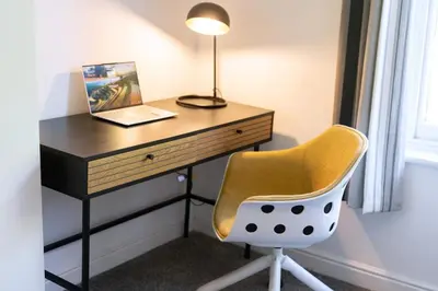 a desk with a yellow chair and a lamp at The Lytham Retreat - New! Spacious & Luxurious in Lytham St Annes