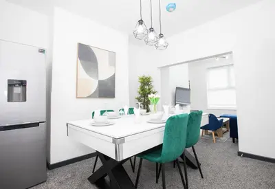 a dining room with a white table and green chairs at Premium Luxury Home by Anfield & City Centre in Liverpool