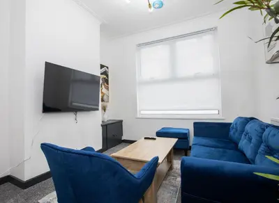 a living room with a blue couch and a table at Premium Luxury Home by Anfield & City Centre in Liverpool