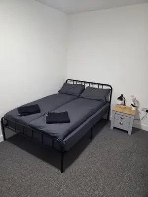 a bedroom with a black bed with a night stand at Quality Rooms in Liverpool