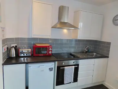 a kitchen with white cabinets and a red microwave at 1 Double Bedroom Great Location - Holmfield Road in Blackpool
