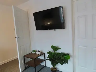 a flat screen tv hanging on a wall with a plant at 1 Double Bedroom Great Location - Holmfield Road in Blackpool