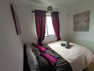 a bed in a bedroom with purple curtains and a window at #72 Stylish 3 bedroom sleeps 7 Wigan House in Pemberton
