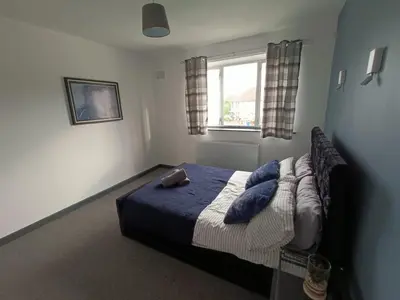 a bedroom with a bed with a blue blanket and a window at #72 Stylish 3 bedroom sleeps 7 Wigan House in Pemberton