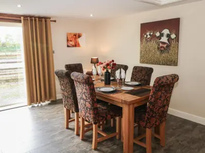a dining room with a wooden table and chairs at Pompian Lodge in Leyland