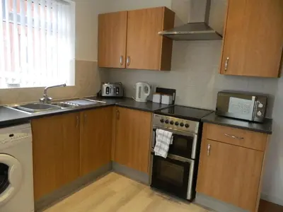 a kitchen with wooden cabinets and a stove top oven at Blackpool San Remo Bungalows 9 & 10 in Blackpool