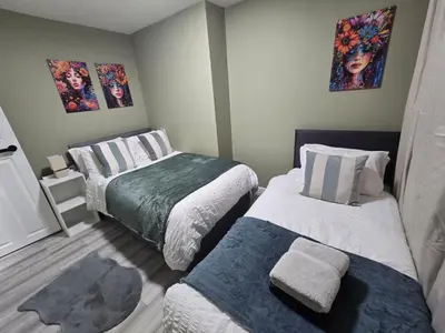 a small bedroom with two beds and paintings on the wall at House 5 Minutes from Sefton Park in Liverpool